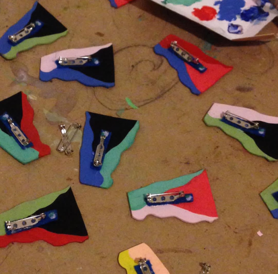 Colorful handmade fabric brooches with metal clasps on studio floor