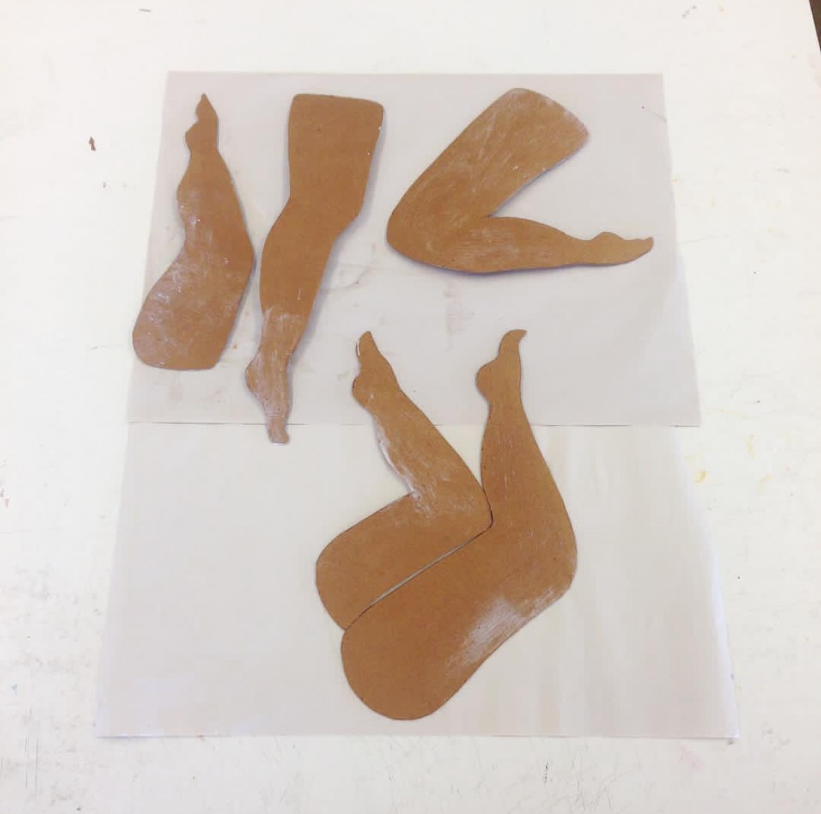 Clay sculptural leg forms arranged on paper