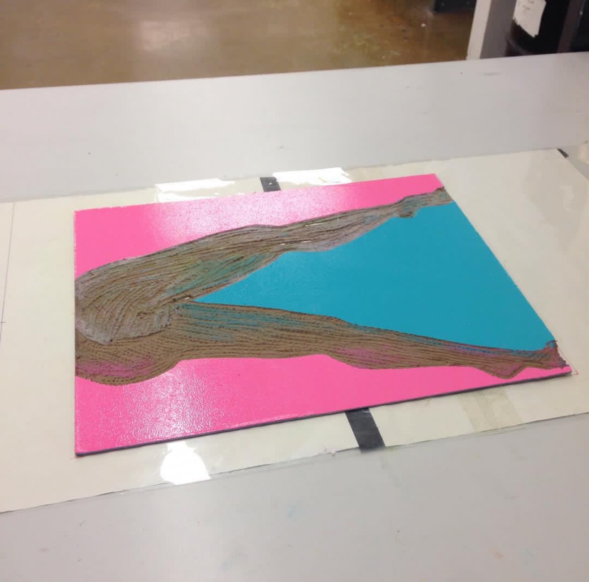 Carved woodblock with pink and teal paint on table