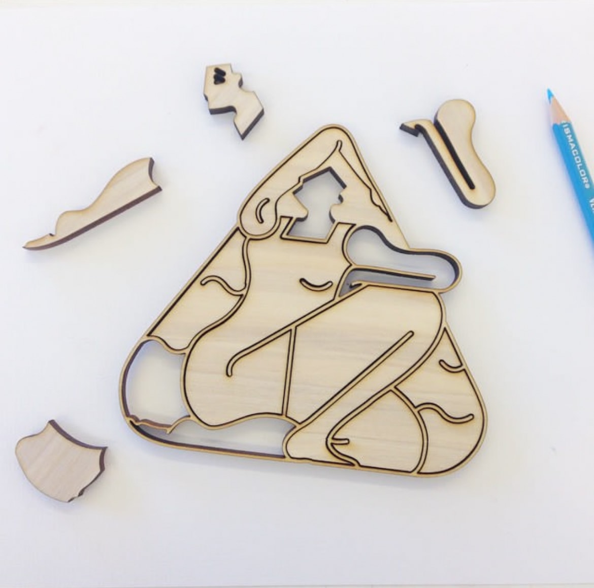 Laser-cut wooden figure puzzle pieces on white surface