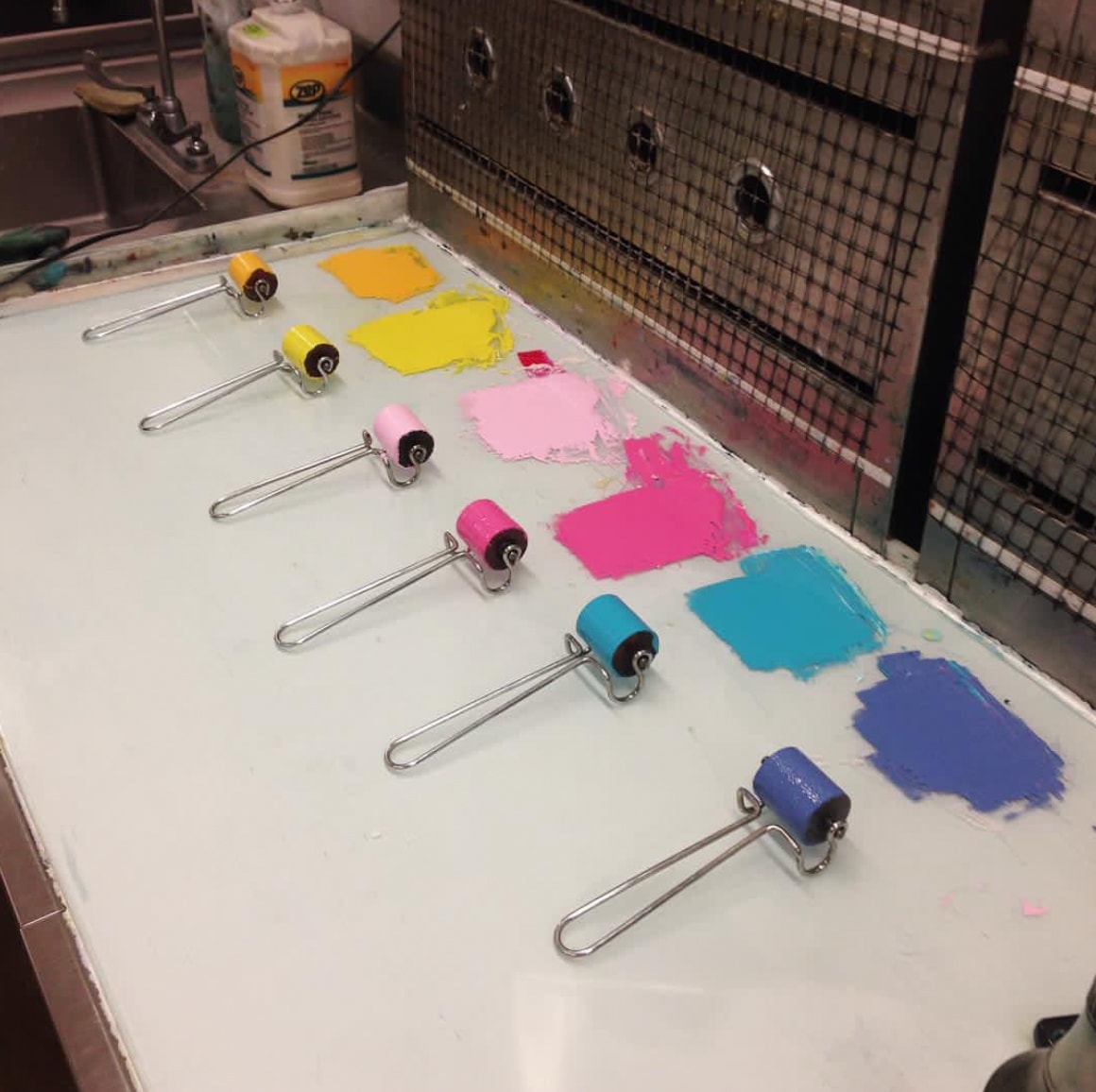 Ink rollers with rainbow paint swatches on printmaking table