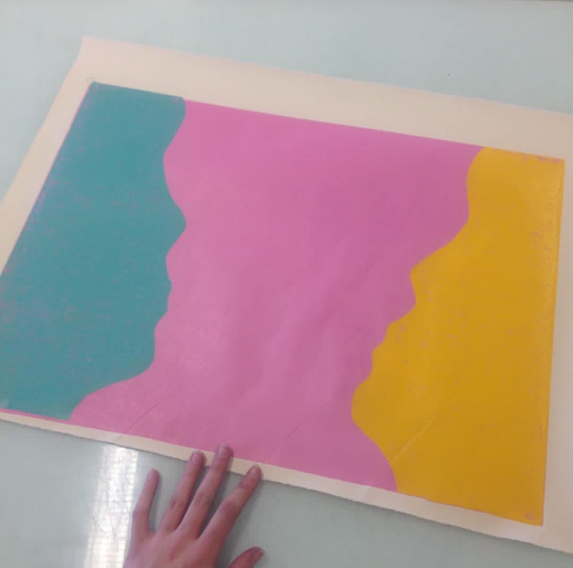 Teal pink and yellow print held by hand on table
