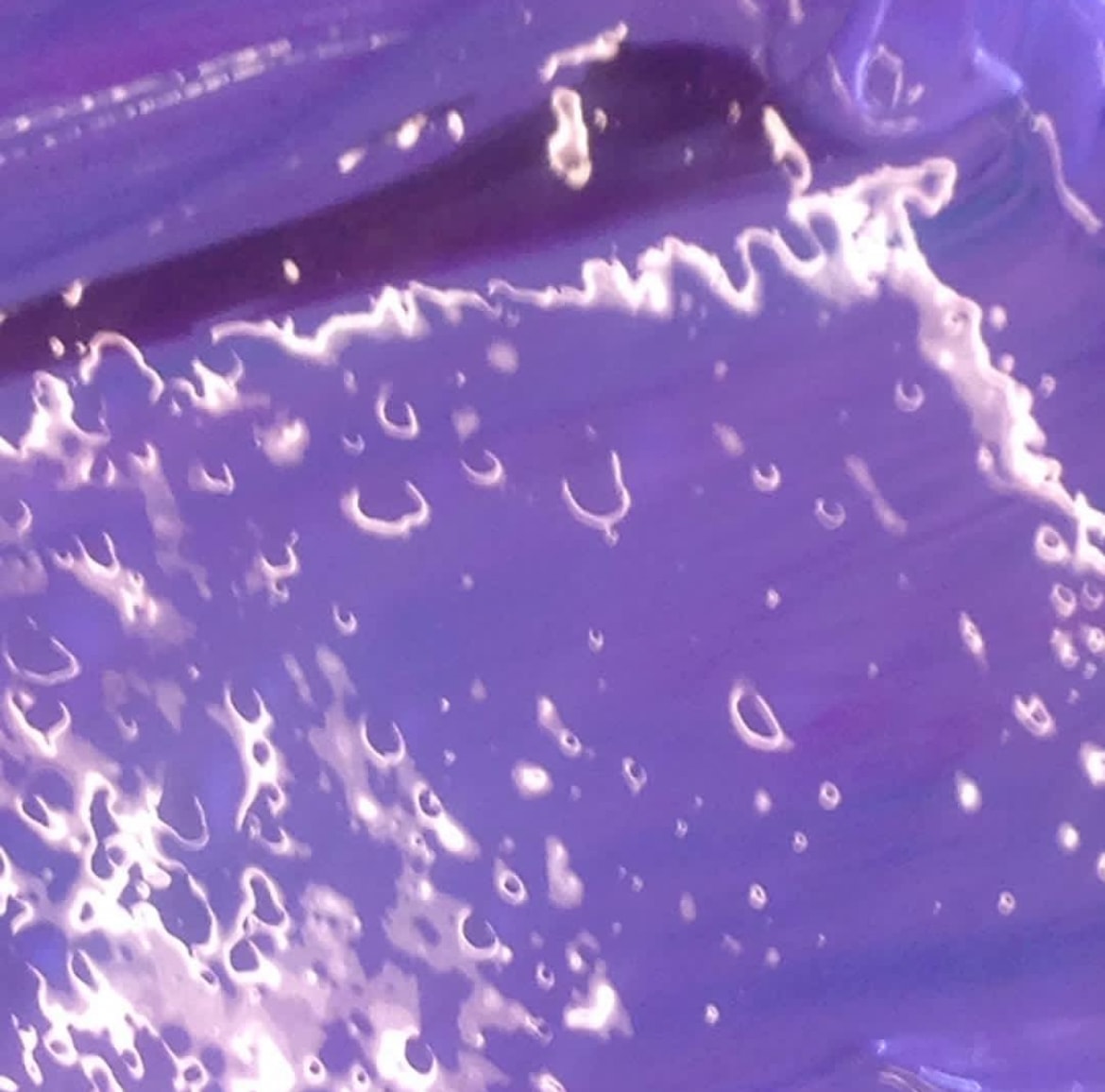 Close-up of wet purple paint texture